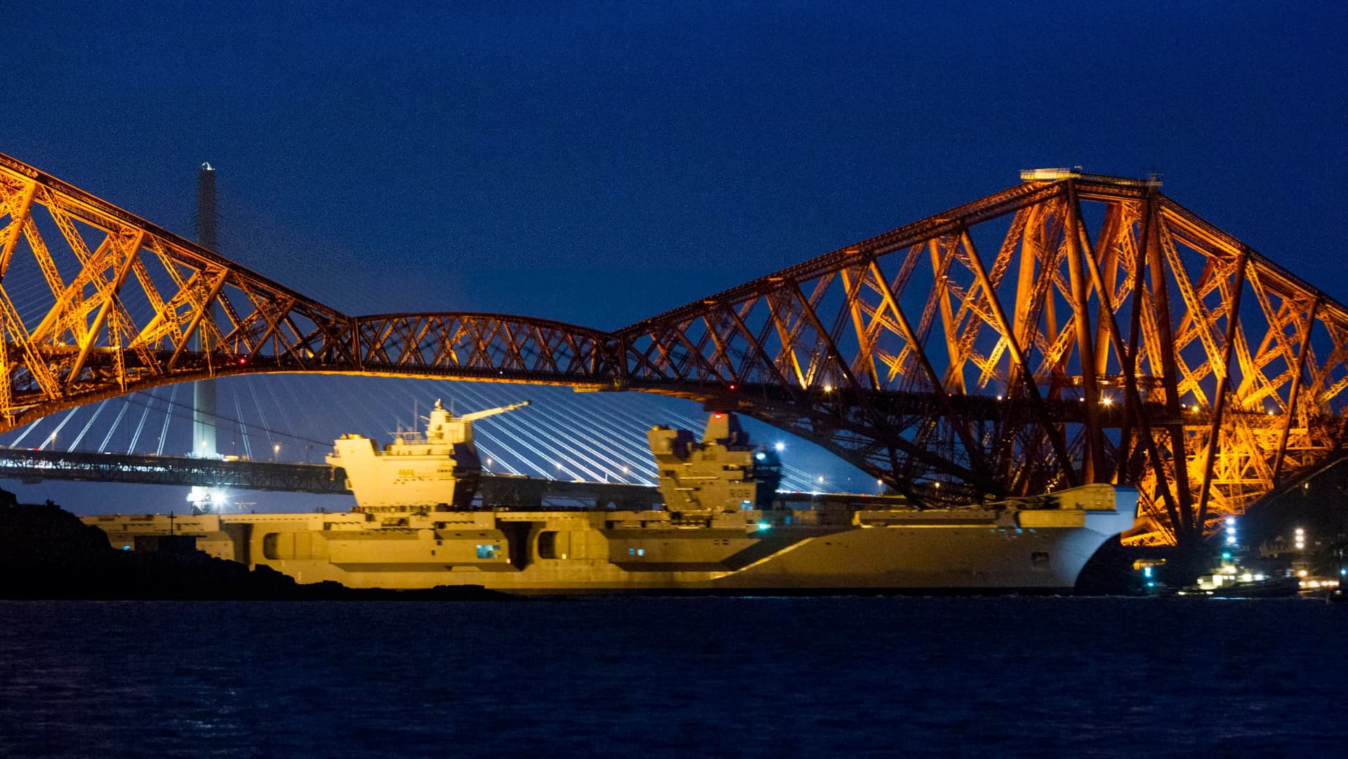 HMS Queen Elizabeth passing beneath the Forth Bridges at night on departure from Rosyth
