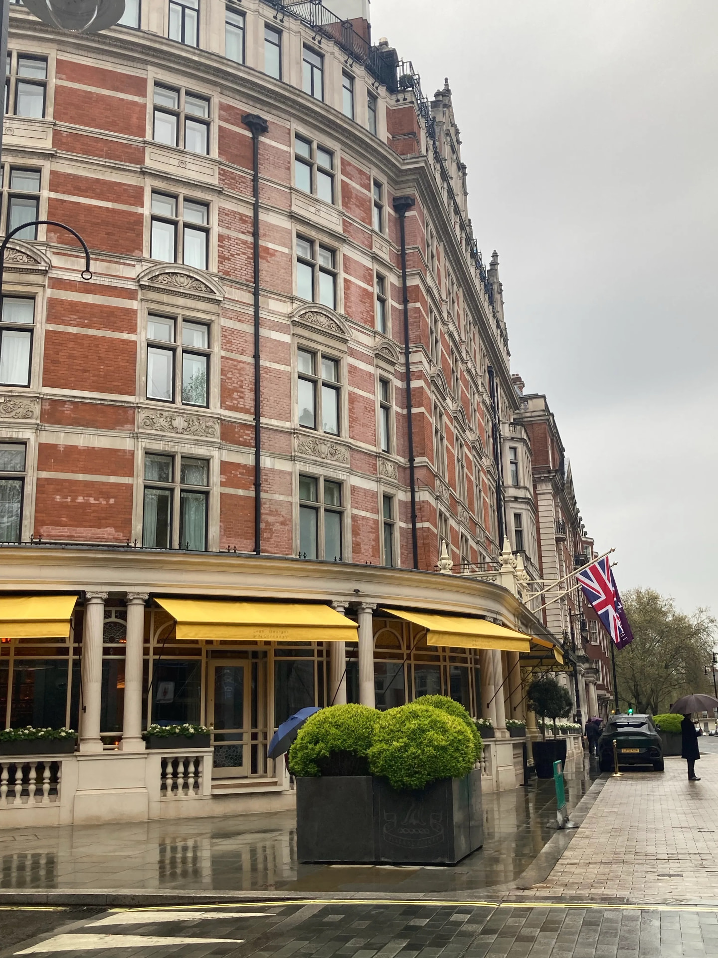 The Connaught at Carlos Place in the rain, yellow awnings and a Union flag